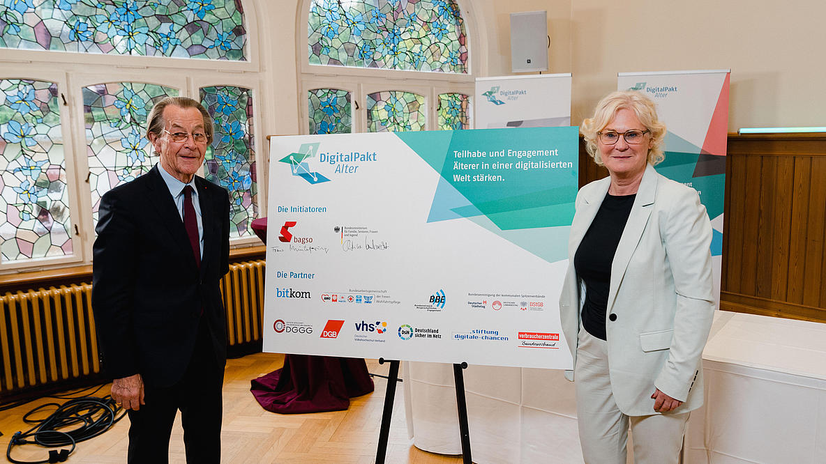 Franz Müntefering und Christine Lambrecht stehen neben einer Tafel mit den Logos der 10 Partner des DigitalPakts Alter