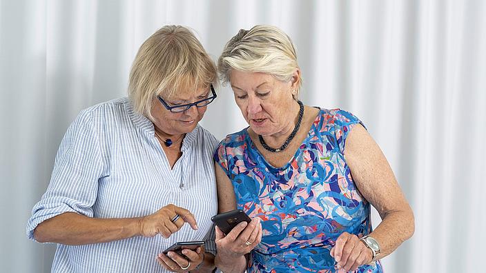 Zwei Frauen schauen gemeinsam auf ein Smartphone. 